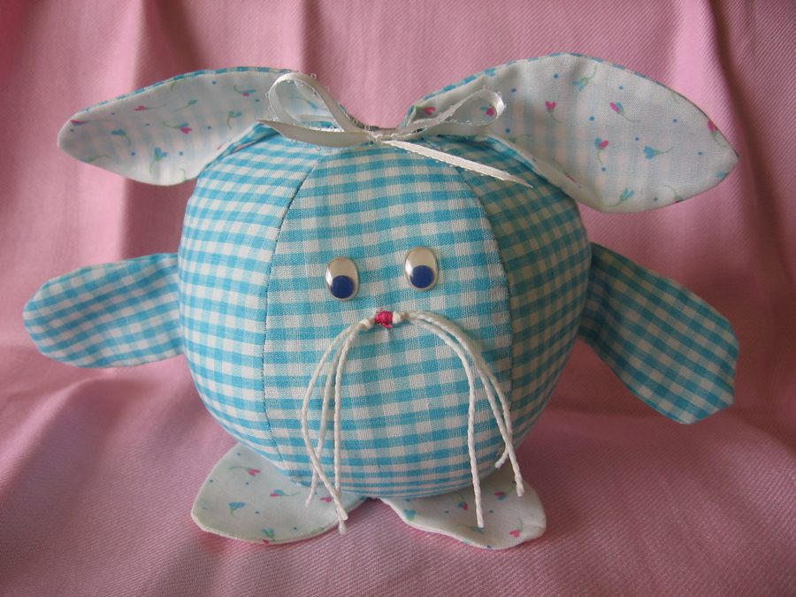 A plump handmade bunny ball with patterned fabric, ears, and tiny tail.